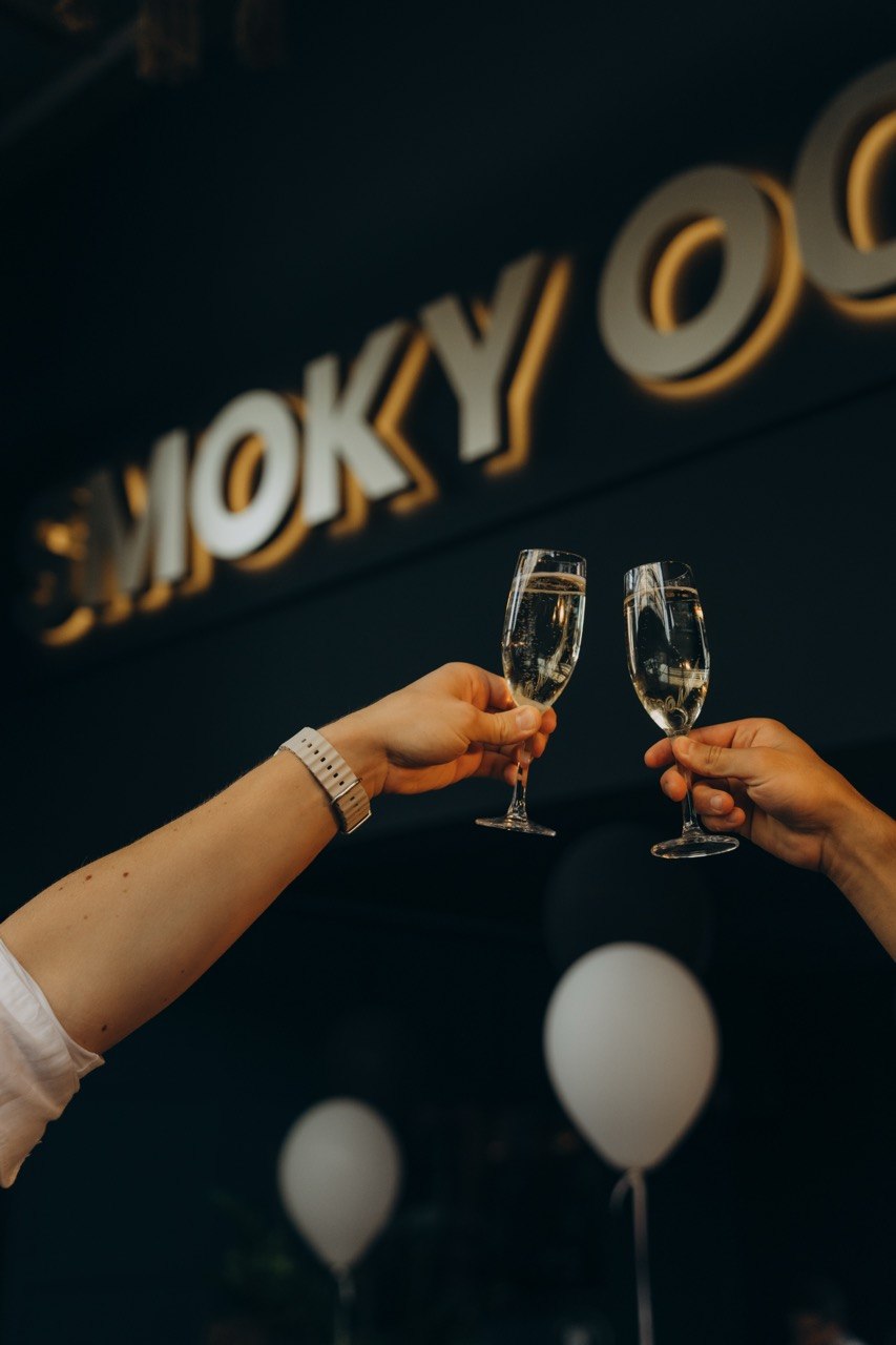 Guests toasting with champagne under the Smoky Ocean sign at a private event