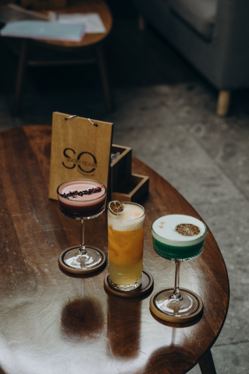 Three signature cocktails next to the Smoky Ocean menu